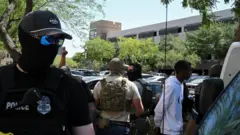 Policiais mascarados, incluindo agentes do HSI e do ICE, levam pessoas sob custódia em um tribunal de imigração em Phoenix, Arizona, EUA, em 21 de maio de 2025.
