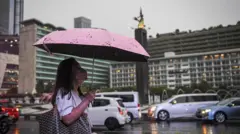 Seorang warga menggunakan payung saat turun di kawasan Bundaran Hotel Indonesia, Jakarta, Selasa (4/10/2022).