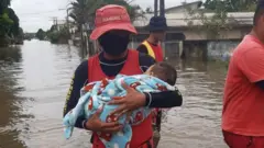 Bombeiro Leandro Simões segura bebê no colopixbet grupo telegramárea alagada