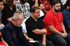 Lulinha sentado ao lado de Lula