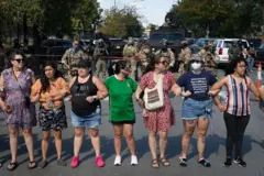 Un grupo de mujeres tomadas de los brazos haciendo frente a agentes migratorios en Chicago