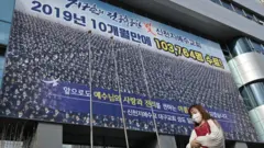 A woman wearing a face mask walks in front of the Daegu branch of the Shincheonji Church of Jesus, 27 February 2020