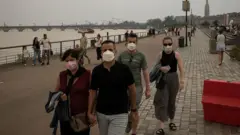 Bordeaux belvárosában maszkot hordó emberek sétálnak. Az ég a füsttől ködös.