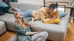 Duas mulheres sentadas conversando e rindo dentro de casa