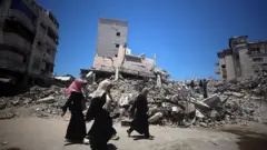 Üç kadın molozların önünden yürüyor. 