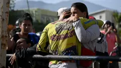Dos personas se abrazan tras conocer el daño a su edificio de viviendas en La Guaira