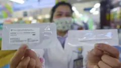 A drug store employee shows a COVID-19 antigen rapid test kit
