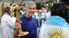 Jorge Messi, pai de Lionel Messi, mostra um troféu para a câmera