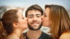 Дві дівчини цілують хлопця — стокове фото