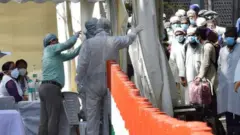 People who took part in a Tablighi Jamaat function earlier this month are checked by a health team before being taken by bus to a quarantine facility amid concerns of infection.
