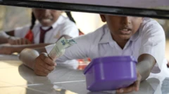 පාසල් දරුවෙක් සහ දැරියක් කෑම මිලදී ගන්නා ආකාරය පෙනේ.