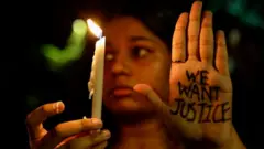 A woman holds a candle during a vigil condemning the rape and murder of a trainee medic at a government-run hospital in Kolkata,