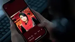زنی در کابل تصویر مرسل نبی‌زاده را در تلفن همراه خود می‌بیند