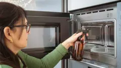 Pessoa pulveriza vinagre em um forno de micro-ondas
