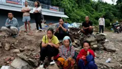 2026年8月27日,尼泊爾努瓦闊特縣特里蘇里,地震倖存者聚集在泥濘堆上等候消息。