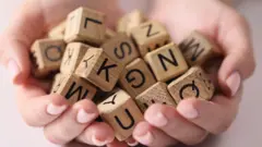 Drewniane kostki z literami gry w Scrabble trzymane w dłoniach - zdjęcie stockowe