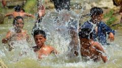 أطفال يسبحون في جدول ماء هرباً من الحر بمدينة مظفرأباد في مقاطعة بلوشستان بباكستان 