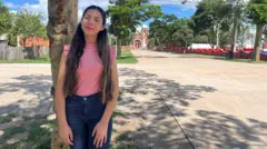 Agustina Sosa apoiada em árvore na rua