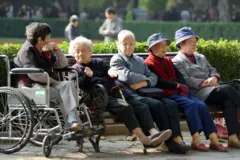 Um grupo de mulheres idosas sentadas em um banco no Parque Fuxing, em Xangai