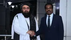 আমির খান মুত্তাকি ভারতীয় একজন কর্মকর্তার সঙ্গে হাত মেলাচ্ছেন 