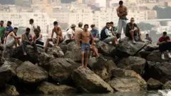 Homens sentados em uma rocha no mar