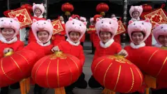 Pipo wear pig hats dey hold red lanterns