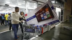 Par izlazi iz radnje sa televizorom u korpi