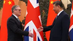 施紀賢（左）與習近平（右）在北京人民大會堂握手，背景是兩國國旗（29/1/2026）