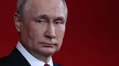 O presidente russo Vladimir Putin de terno, olhando para o lado