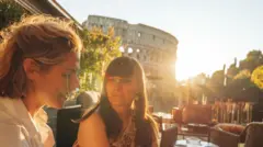 İki kadın, arkalarında Roma'daki Kolezyum var. Güneş parlıyor