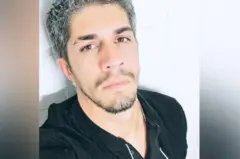 Claudio Barrelier olhando para a câmera em uma selfie. É um homem branco, jovem, de cabelos grisalhos. Ele usa uma blusa preta.