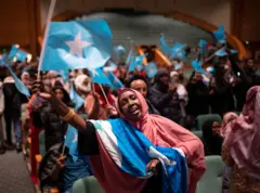 Inmigrantes somalíes bailan y ondean la bandera de Somalia en el auditorio del Centro de Convenciones de Minneapolis a la espera de la llegada del presidente somalí Hassan Sheikh Mohamud, diciembre 2022