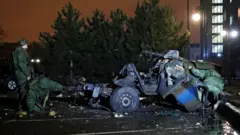 Specialists inspect a wreckage of a car that, according to the local authorities, was blown up near the government building, in the rebel-controlled city of Donetsk, Ukraine February 18, 2022