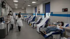 Milano'da bir kadın koronavirüs nedeniyle kan bağışında bulunuyor