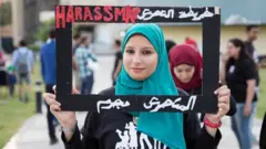 امرأة تحمل لافتة مطالبة بفضح المتحرشين في مصر