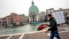 Homem andando com máscara em Veneza.