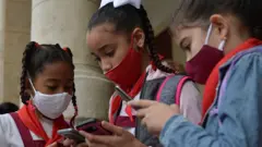 Alumnas de una escuela mirando sus celulares