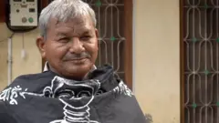 Lal Bihari Mritak sentado em entrevista, em área externa