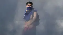 Joven emerge entre la humareda en las protestas en Chile.