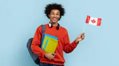 Man dey wave Canadana flag as im carry books 
