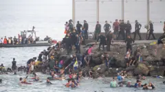 Migrants swimming to shore off Ceuta. 