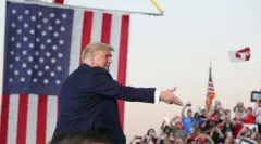 El presidente Donald Trump lanza mascarillas MAGA a la multitud de simpatizantes a su llegada a un mitin de campaña en el Aeropuerto Internacional Orlando Sanford, en Sanford, Florida, el lunes 12 de octubre de 2020.