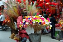 Một chị bán hoa giả và hoa sấy khô đạp xe giữa một đường phố đầy sắc màu vào ngày 31/1/2000, tức 25 tháng Chạp âm lịch