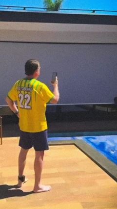 Bolsonaro usa o telefone à beira da piscina da casa onde ele irá cumprir prisão domiciliar