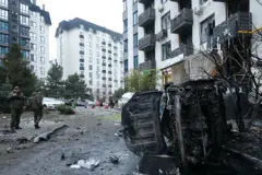 Um carro queimado está tombado em um conjunto habitacional danificado por um ataque com mísseis e drones russos na vila de Sofiivska Borshchahivka, distrito de Bucha, região de Kiev, Ucrânia, em 29 de novembro de 2025