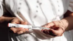 흰색 주사기펜을 들고 있는 여성의 모습