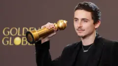 Timothée Chalamet segurando seu Globo de Ouro