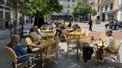 Pessoas sentadas em mesas na calçada em estabelecimento em Madri