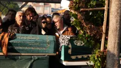 Turan ailesi ve yakınları cenaze namazında saf tutuyor. Baba Tolga Turan ve kızı Eylül Turan, anne Müge Turan ve kızı Alya Turan’ın tabutlarının önünde duruyor.