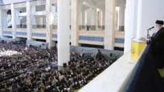 O líder supremo iraniano, o aiatolá Ali Khamenei, segura um fuzil enquanto lidera a oração de sexta-feira na mesquita Imam Khomeini Musalla em Teerã, Irã, em outubro de 2024.